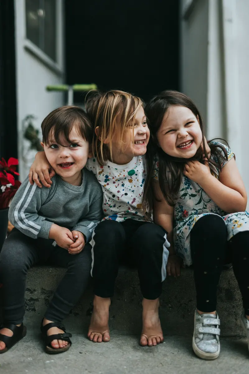 Tres niñas riendo sentadas en un escalón